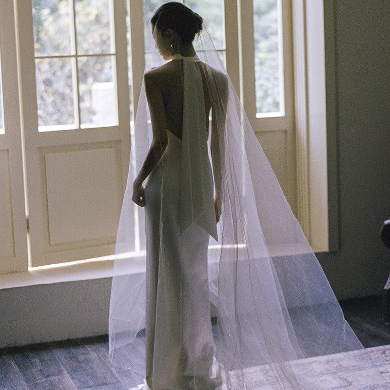 White halter fishtail dress with flowing veil train, back view