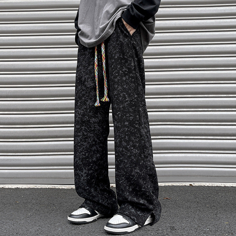 Black straight-leg pants with elastic waistband and multicolor drawstring ties, textured