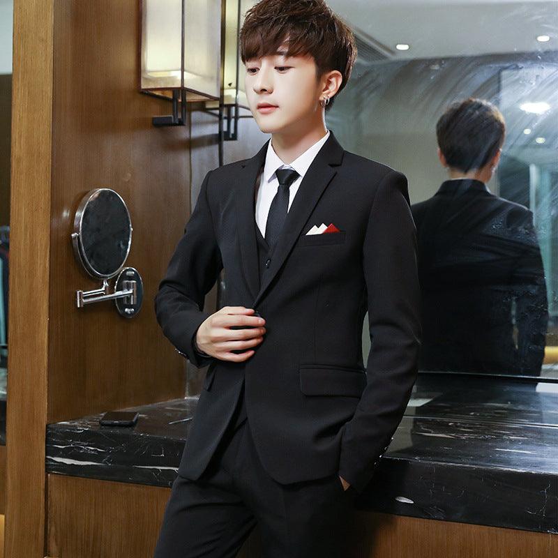 Men's black solid color suit with vest, white shirt, black tie, and pocket square