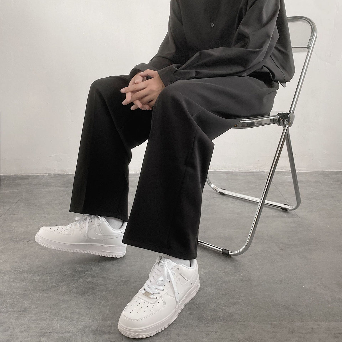 Men's black wide-leg straight trousers with loose fit and visible thigh crease