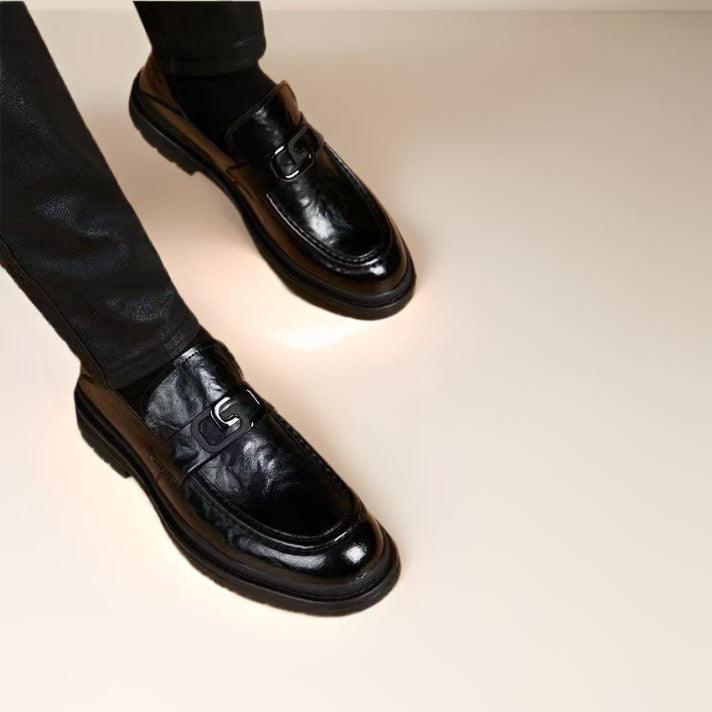 Men's black leather loafers on feet, buckle strap and chunky sole