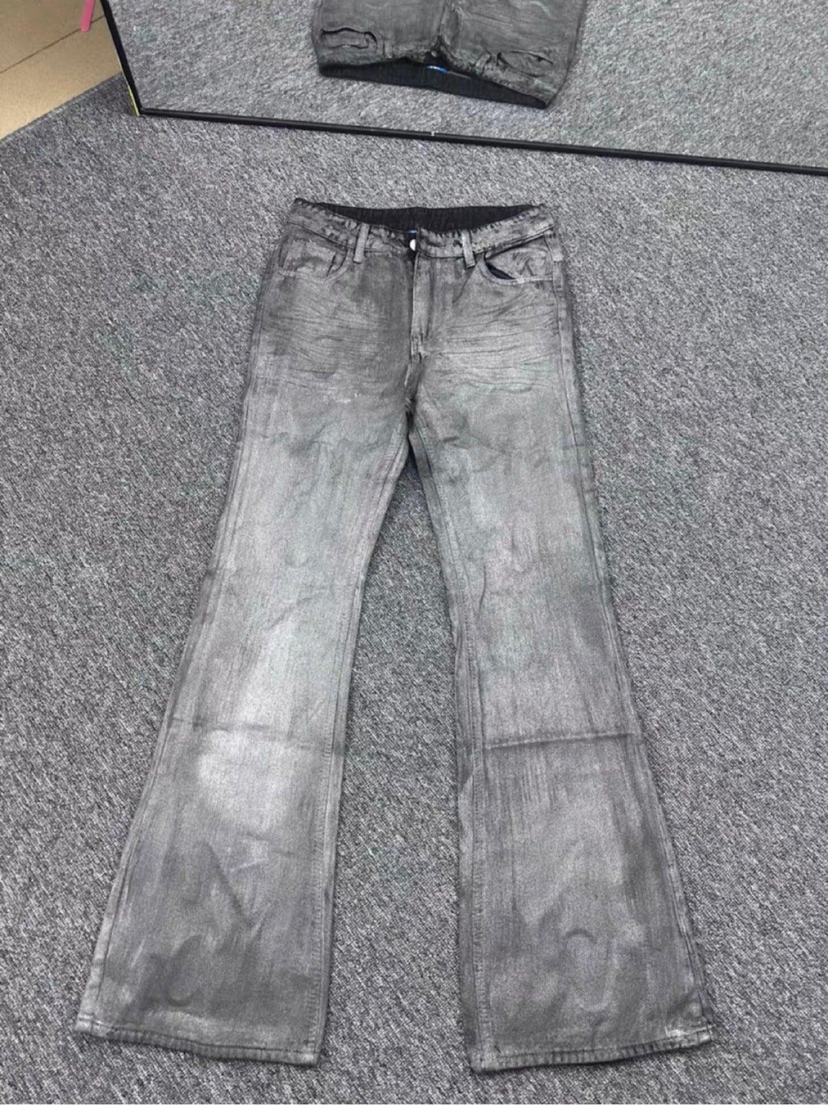 Gray washed distressed denim jeans laid flat, flared straight-leg cut