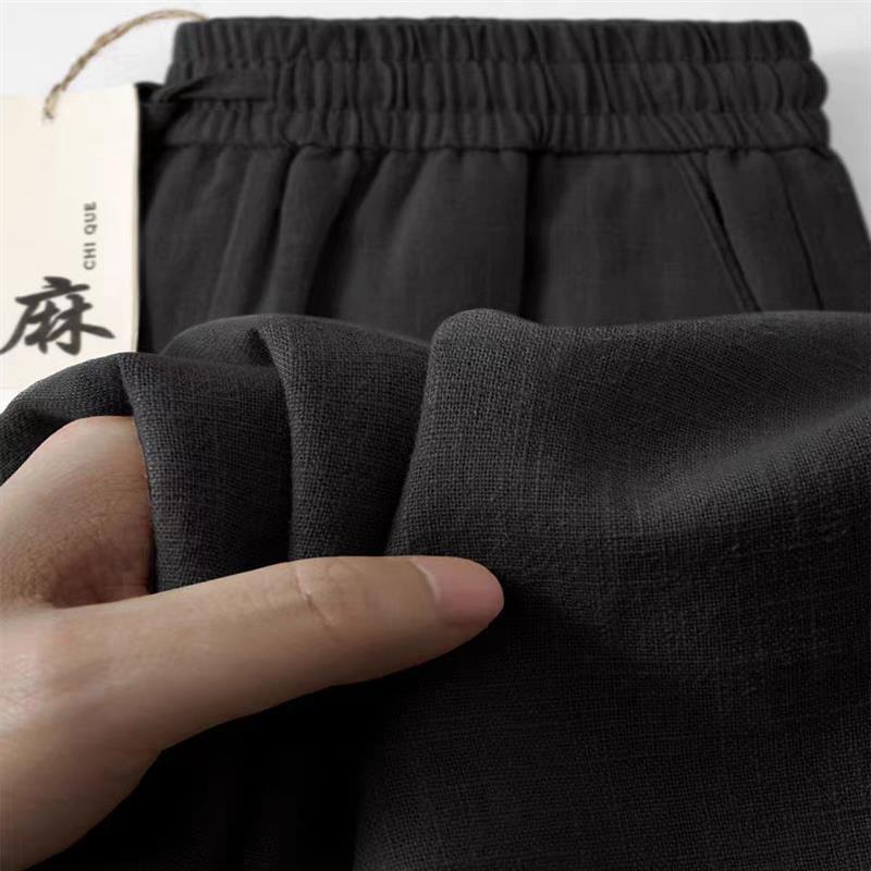 Men's ramie pants, dark gray, elastic waist and draped fabric shown with hand.