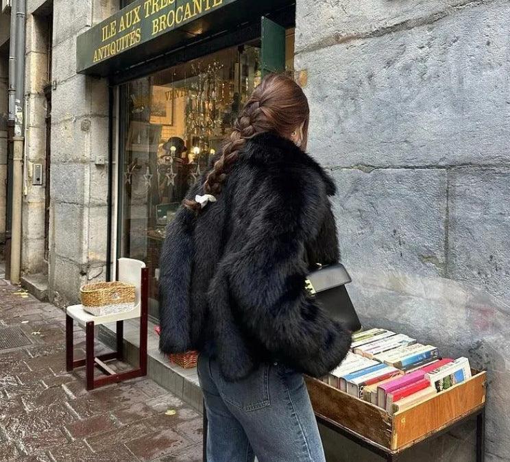 Women’s black fur coat back view with wide lapels and long sleeves over jeans