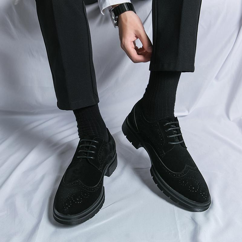 Black lace-up oxford-style leather shoes with brogue perforations and thick sole