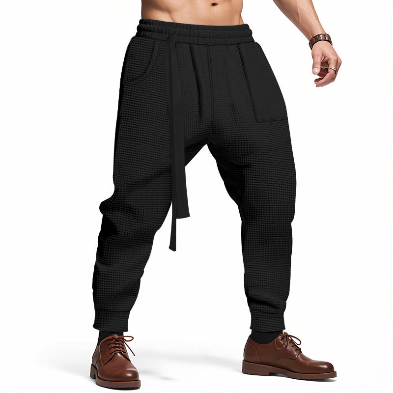 Black waffle track pants with elastic waist, vertical pleats, black drawstring tie