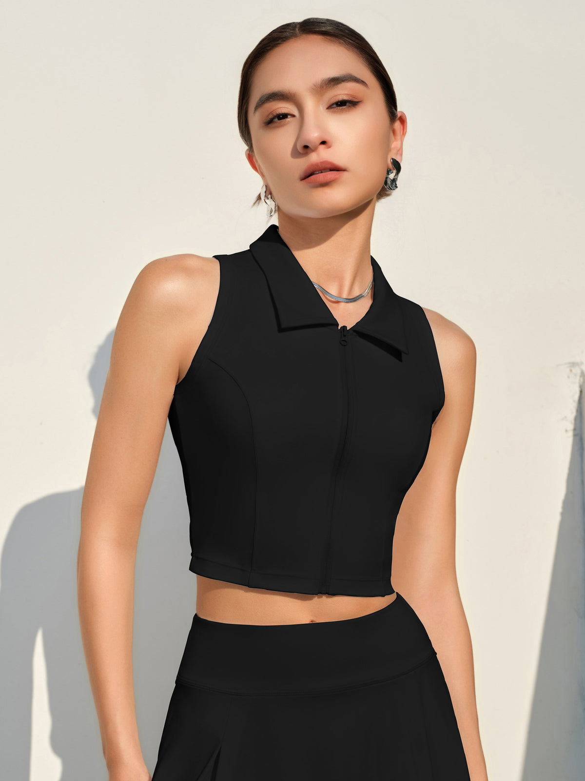 Women's sleeveless sports top, zip-front, black color.