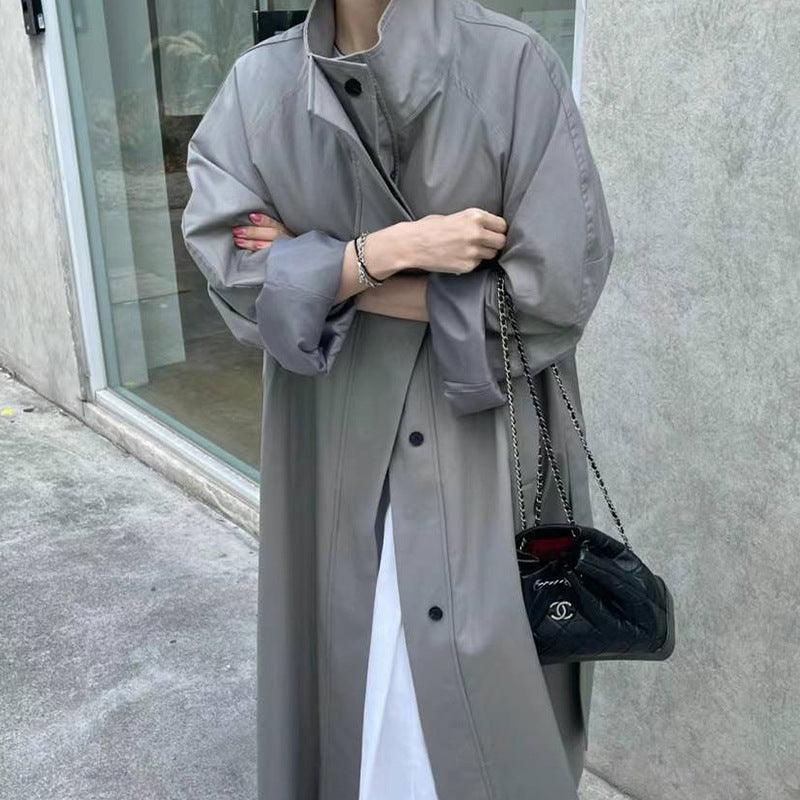 Gray long trench coat worn open with stand collar and button placket