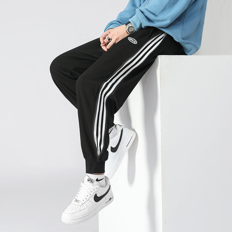 Men's black tapered track pants with white triple stripe on the side