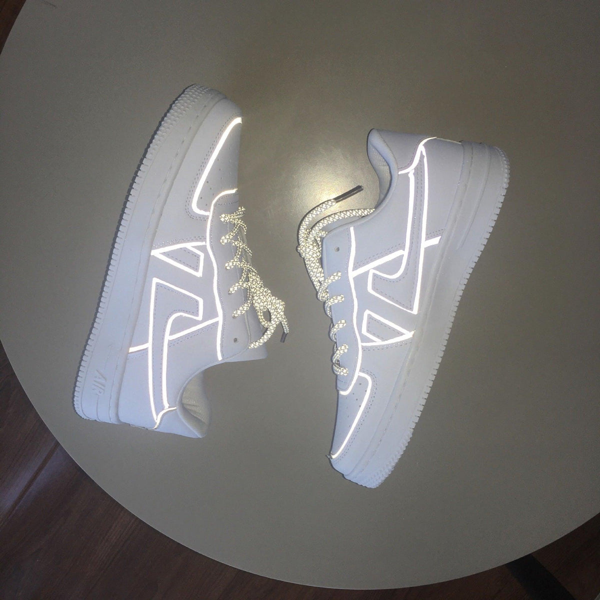 White reflective sneakers, angled pair with glowing heel and toe outline