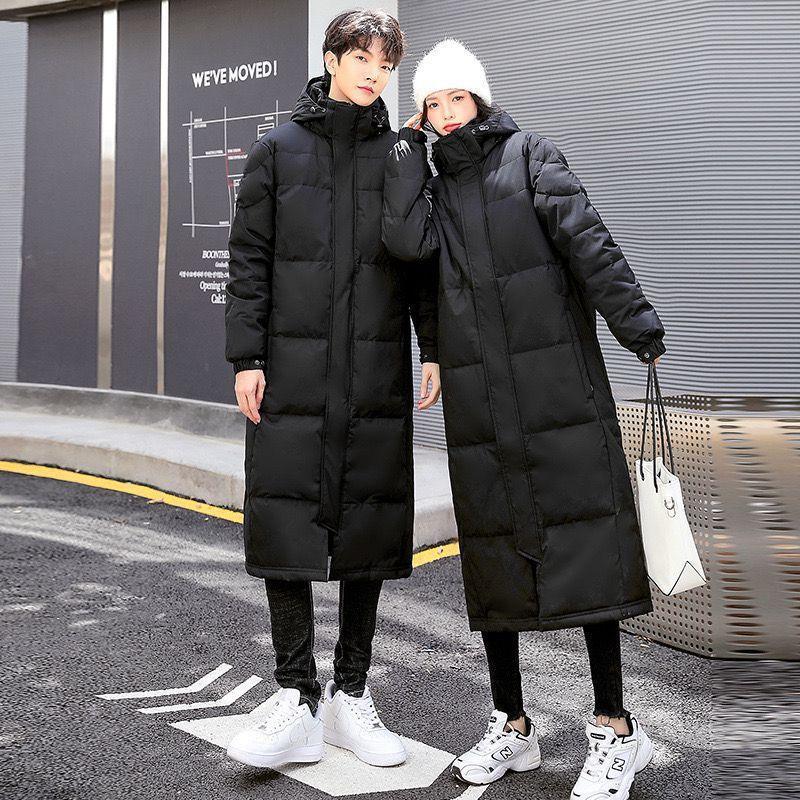 Long black hooded puffer coat with button front and side pockets, worn over dark pants