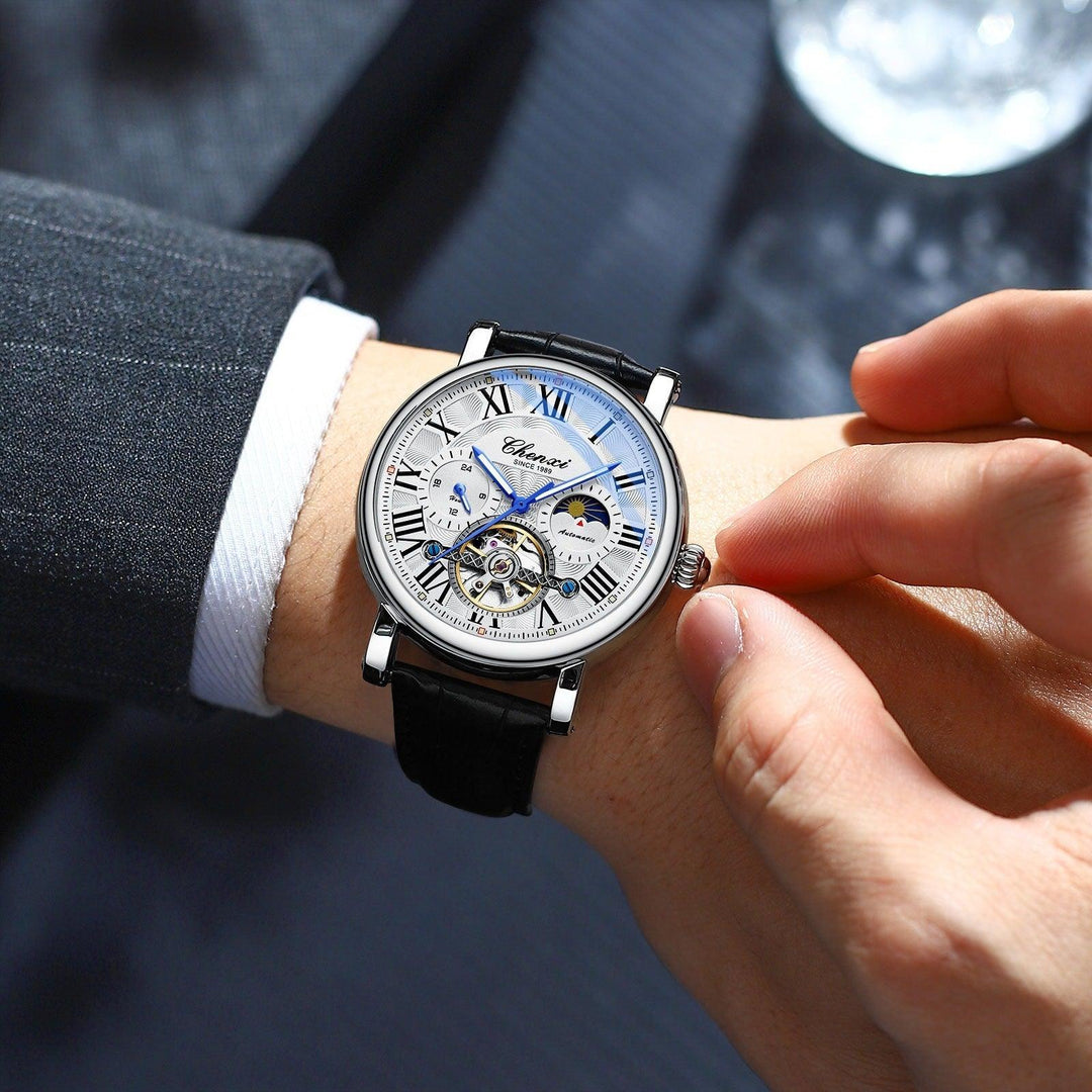 Mechanical watch with white-blue dial, silver case, and black leather strap on wrist