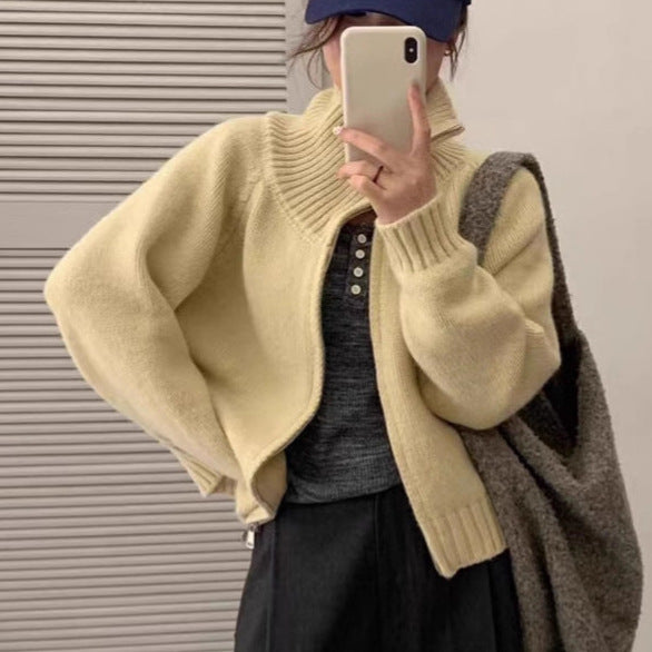 Cream knit short cardigan coat detail with front closure and ribbed hem.