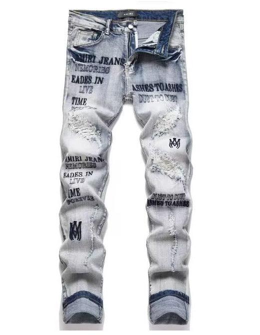 Light blue slim jeans with layered white text graphics and distressed patches