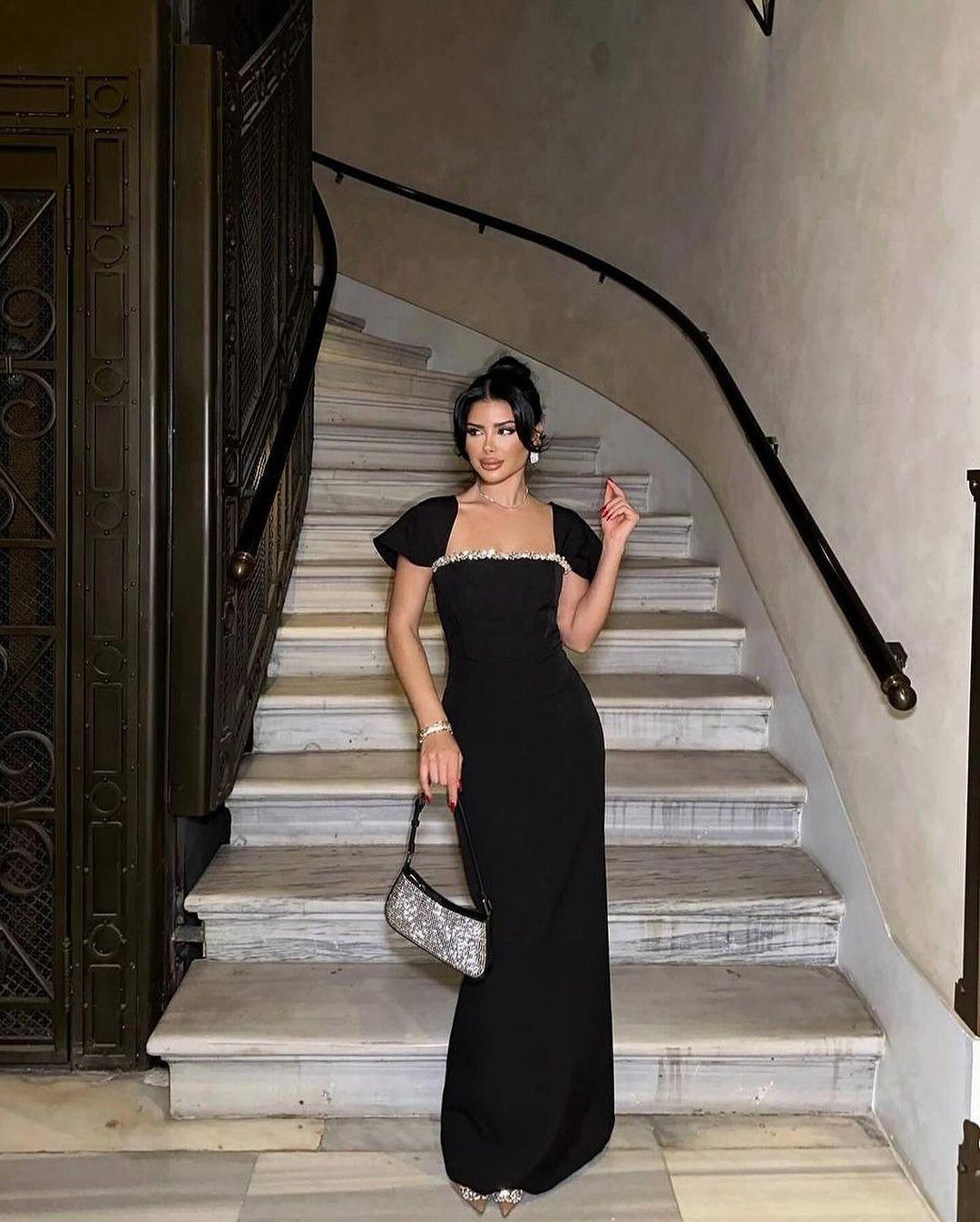Black fitted evening dress with jeweled square neckline, short cap sleeves, floor-length mermaid