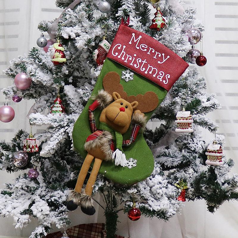 Green Christmas stocking with “Merry Christmas” banner and plush reindeer character on tree display.