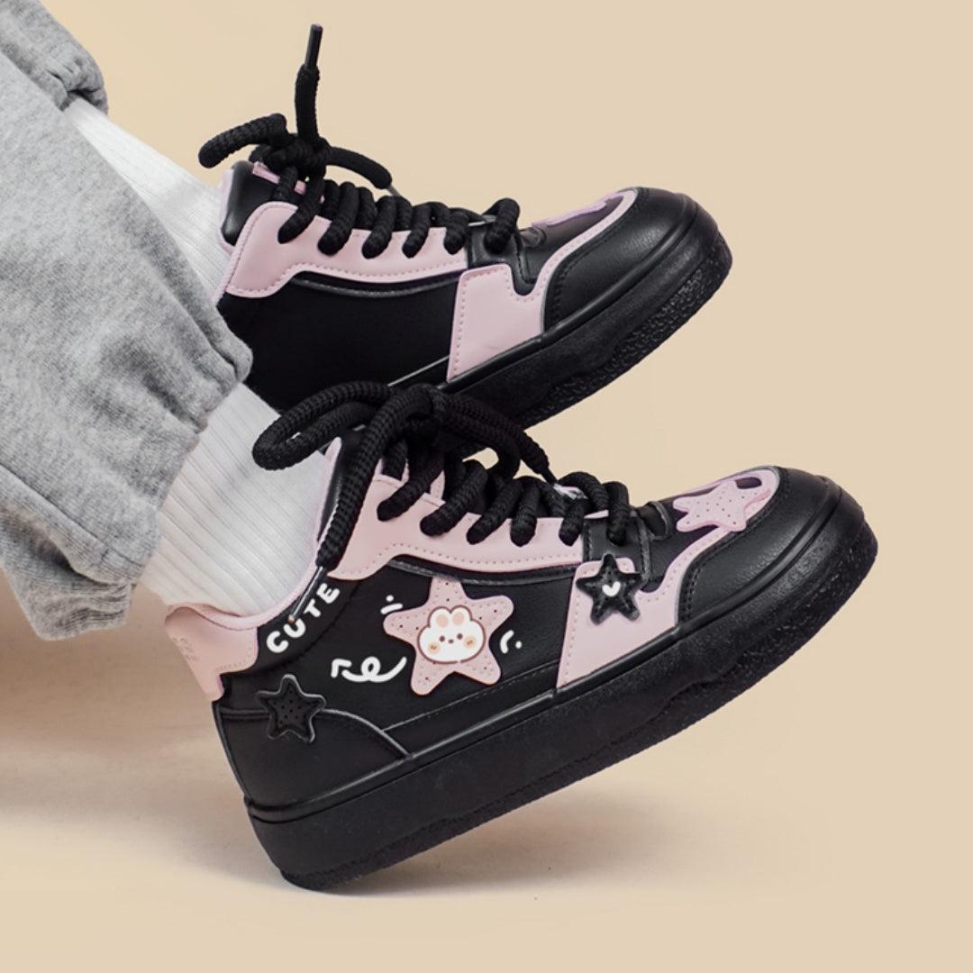 Pair of black high-top sneakers with pink accents, lace-up front, star and bear graphic details