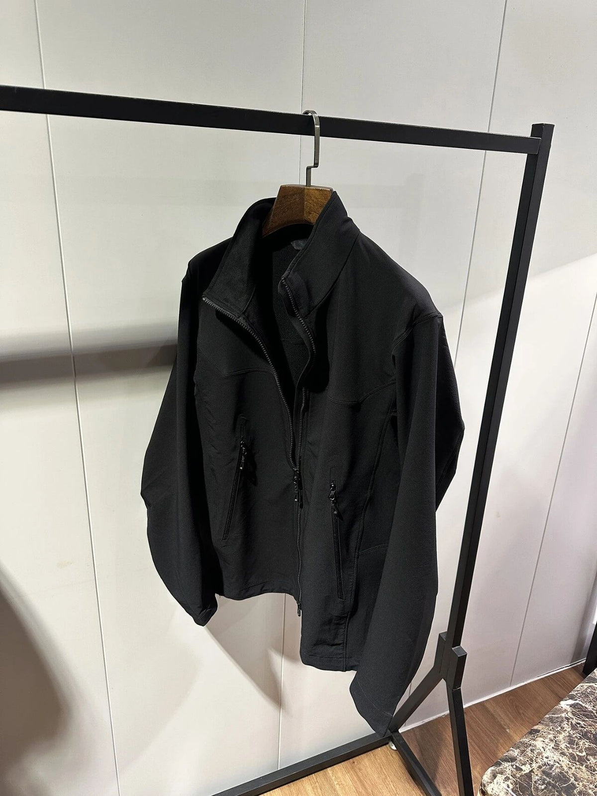 Black zip-up outdoor jacket on hanger with stand collar and front zipper