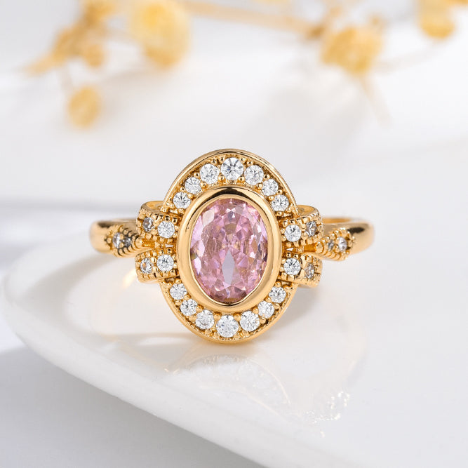 Gold-tone gemstone ring with oval pink center stone and sparkling halo border