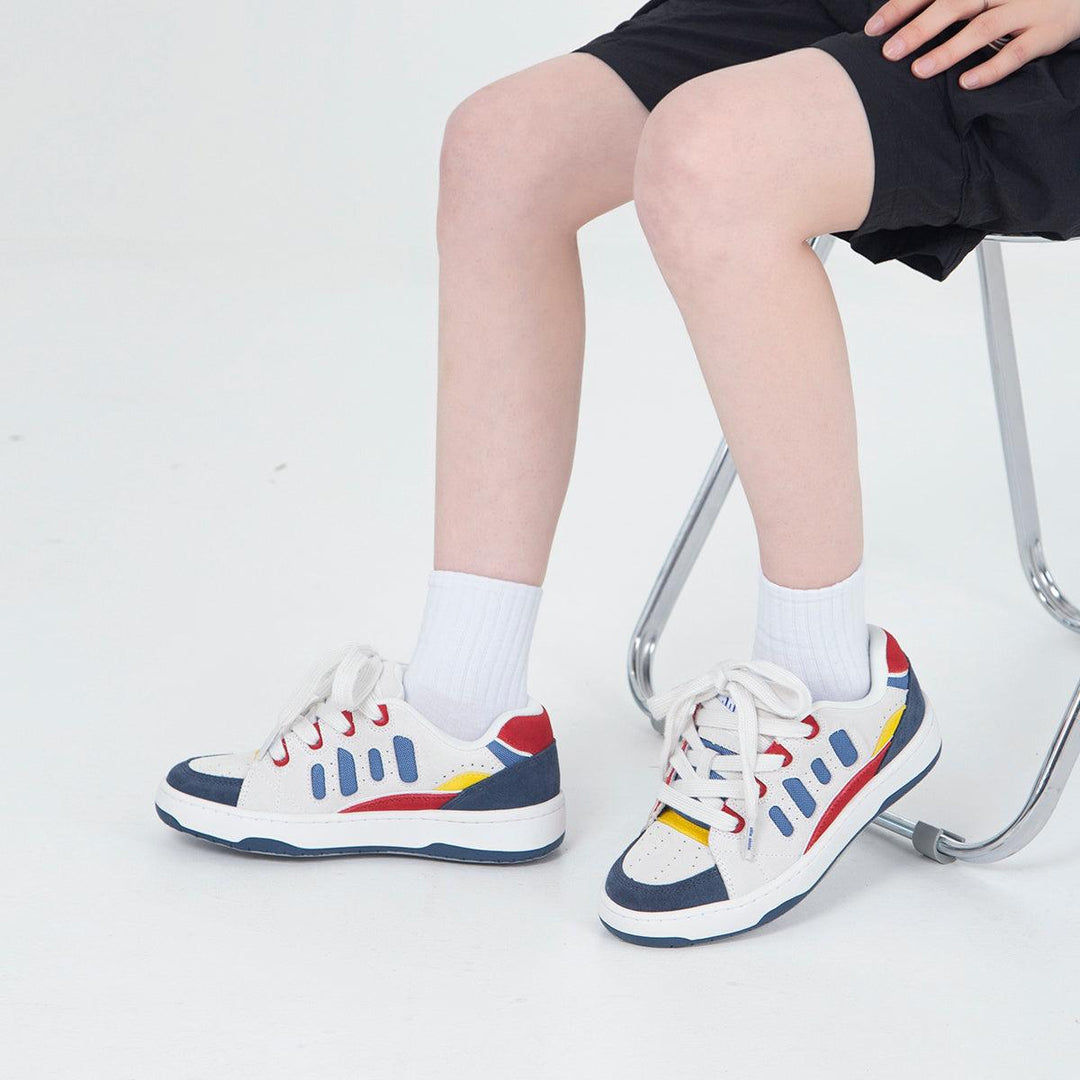 Low-top skateboard shoes in white with blue panels, red accents, yellow details, lace-up.