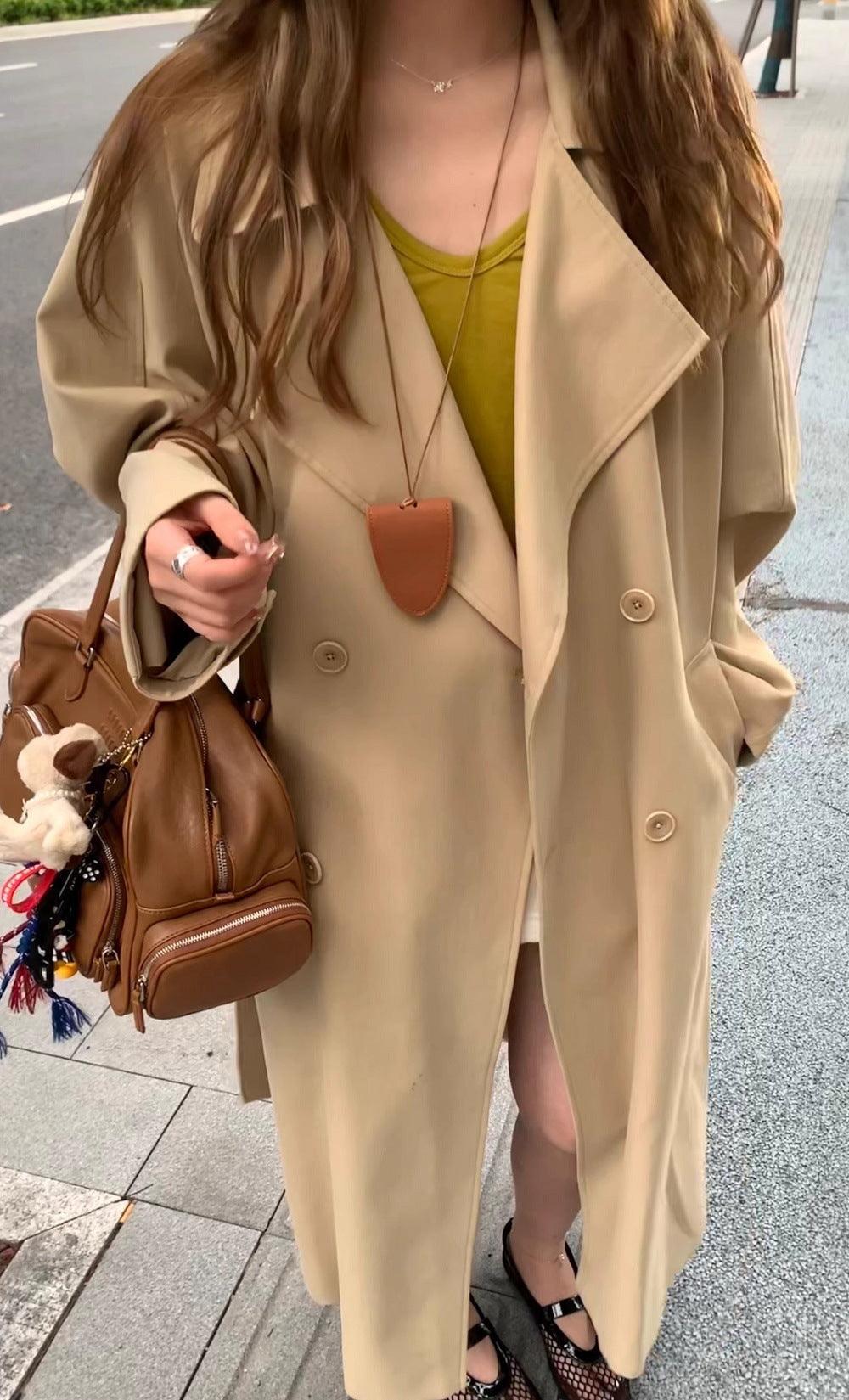 Beige long trench coat with lapel, double-breasted buttons, and front chest pocket.