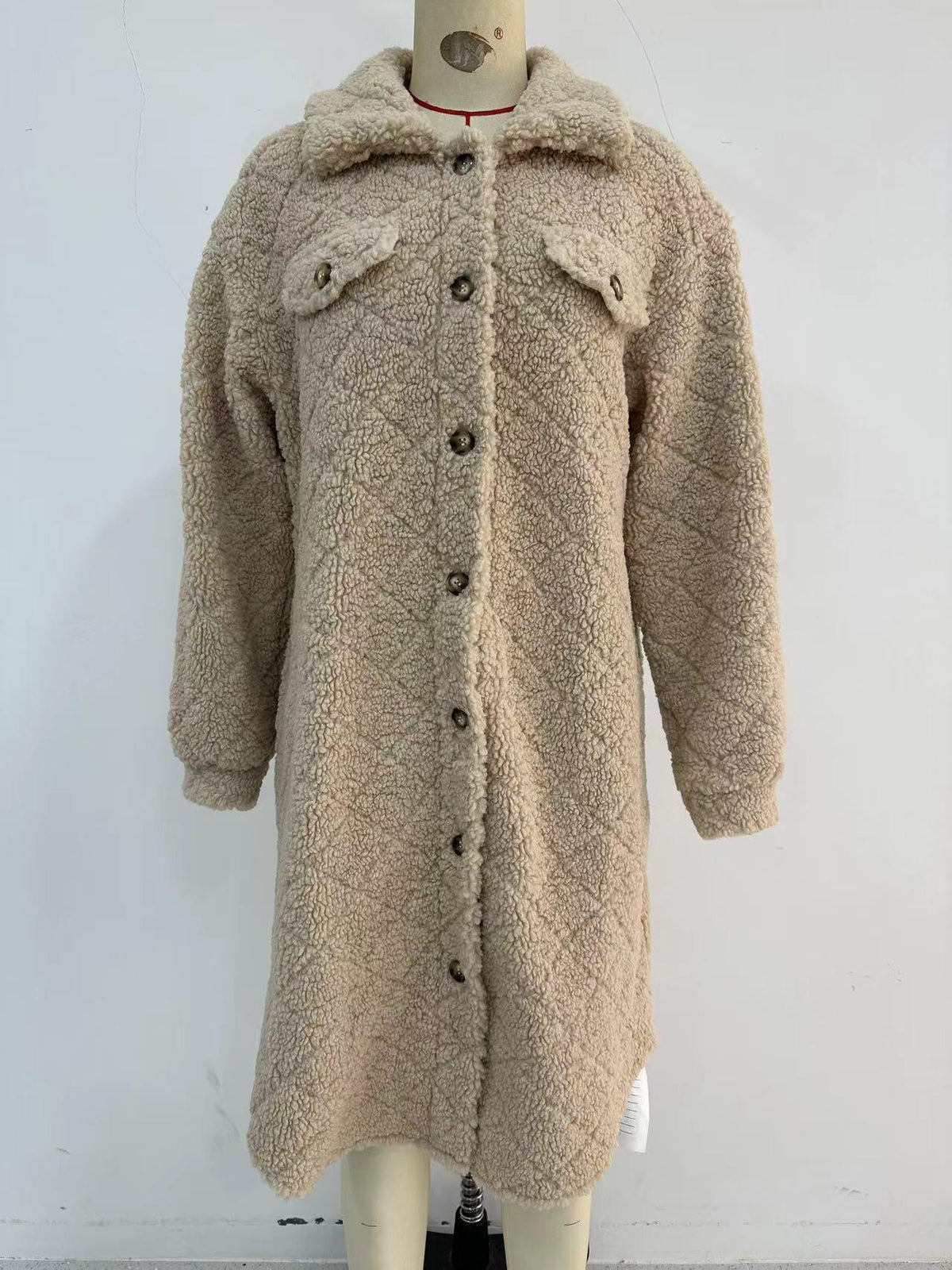 Light beige plush coat on mannequin with button front, large collar, and long sleeves