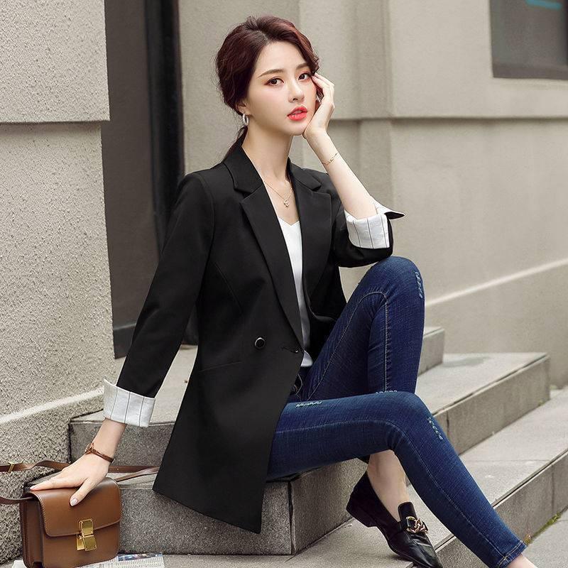 Women’s black blazer with notched lapels and button front, cuffed sleeves over light top
