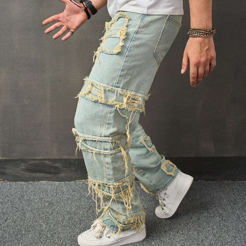 Pale green denim wide-leg trousers with large distressed rips and frayed fringe at hem