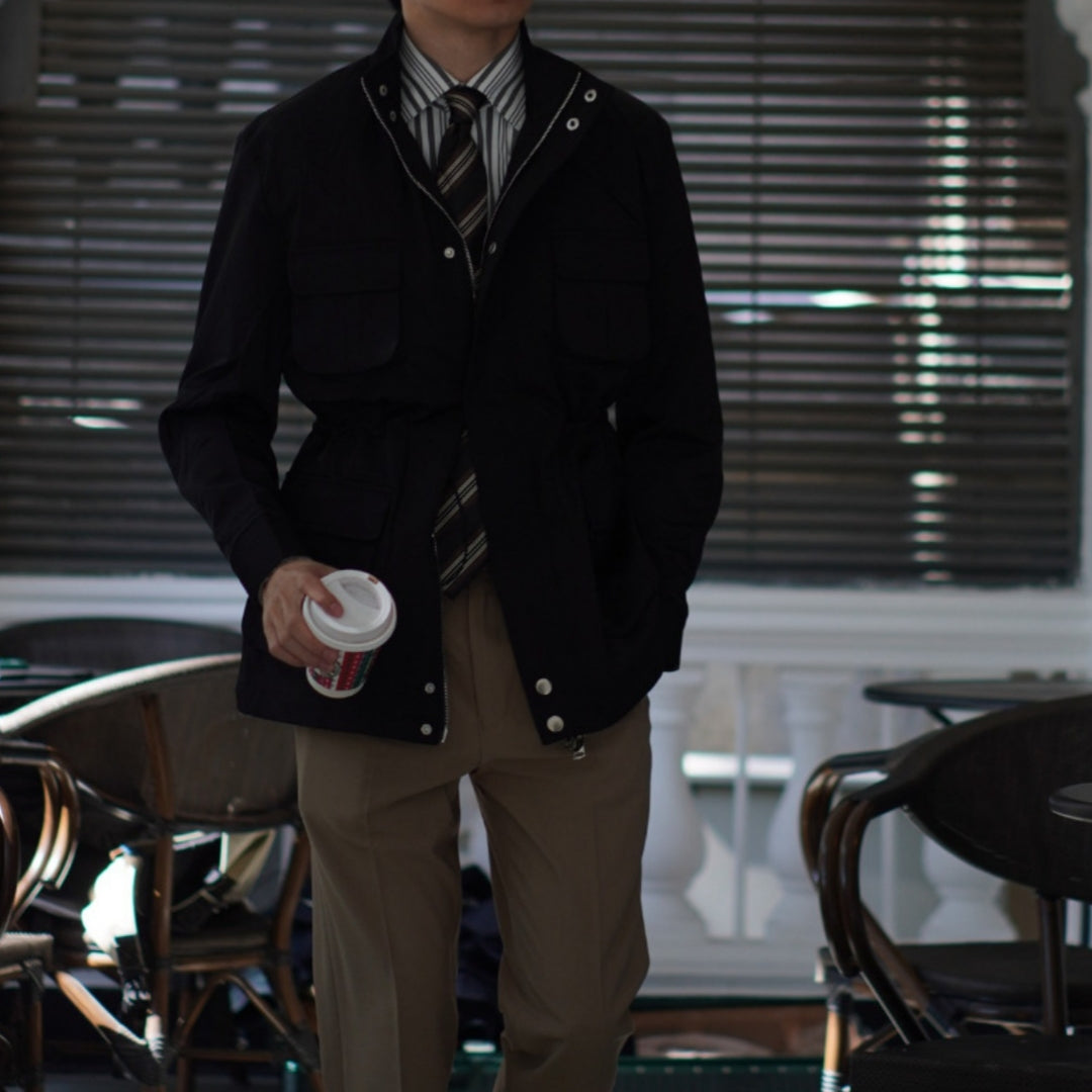 Men's black windbreaker coat with snap buttons and flap pockets, striped shirt and tie