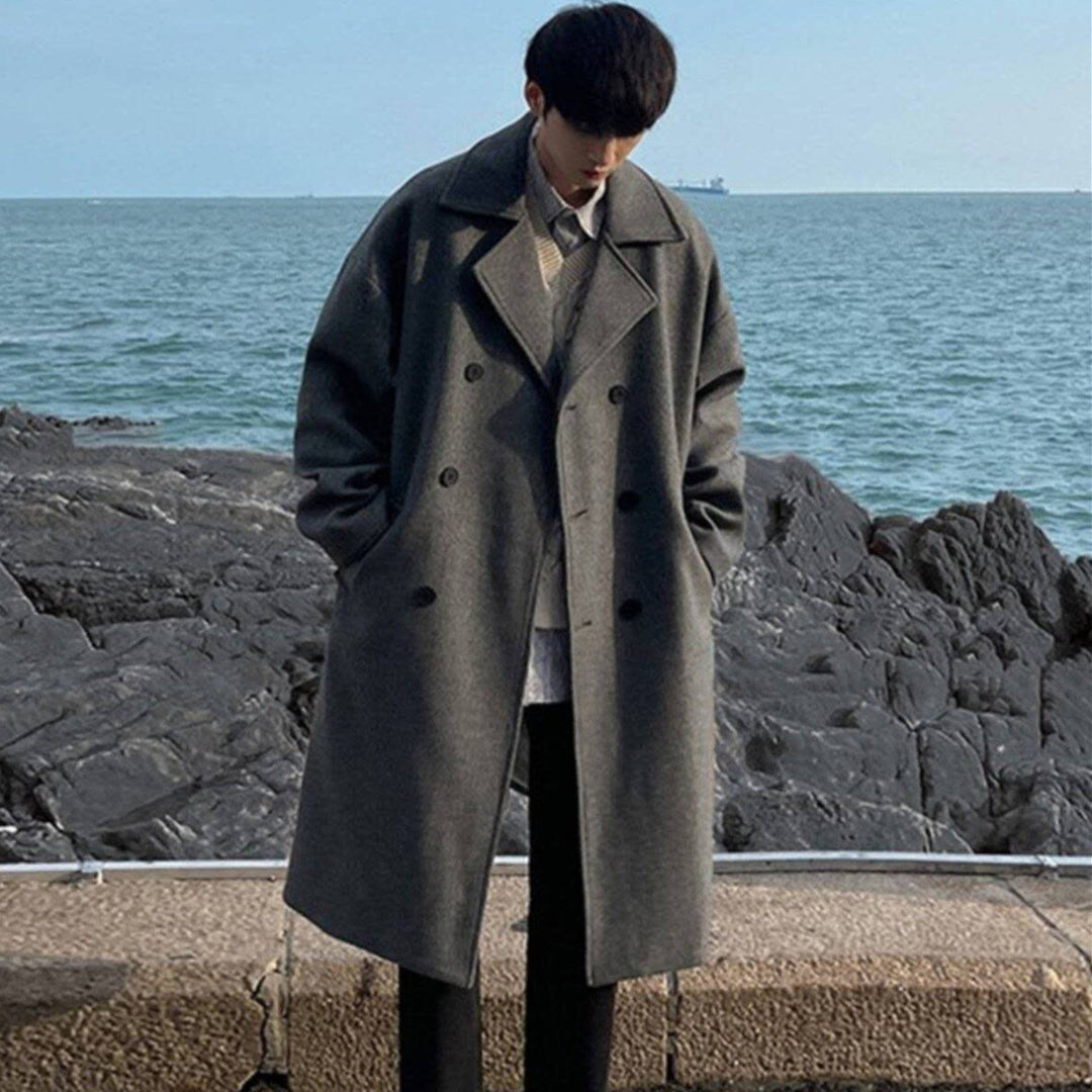 Gray double-breasted wool trench coat with wide lapel collar and longline hem.