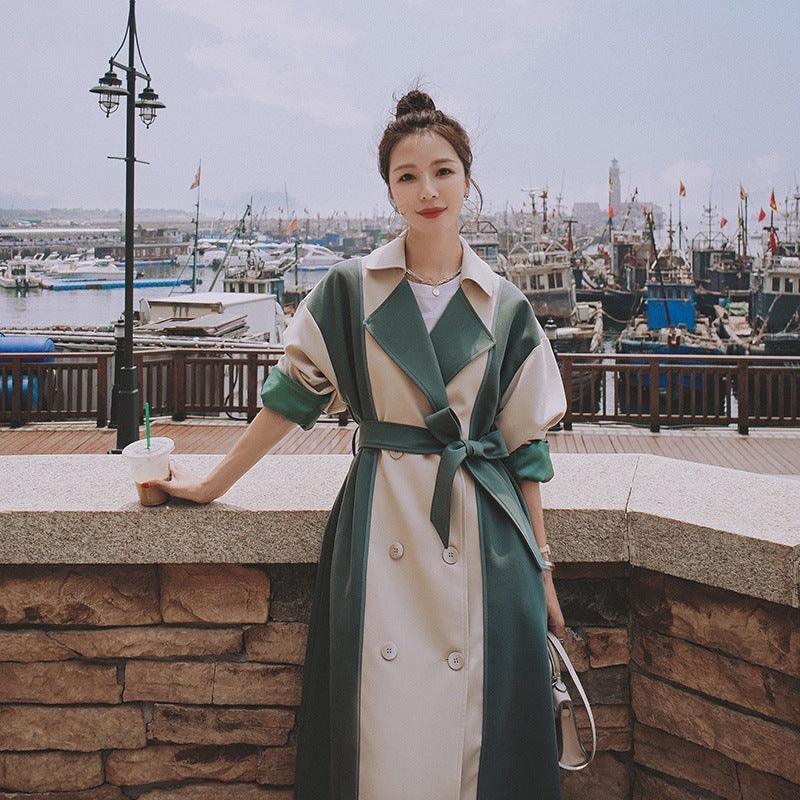 Long trench coat with teal-and-cream diagonal panels, belted waist, double-breasted front