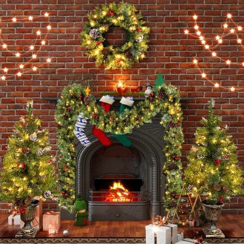 Lit green artificial Christmas trees with pinecones and red ornaments near fireplace decor