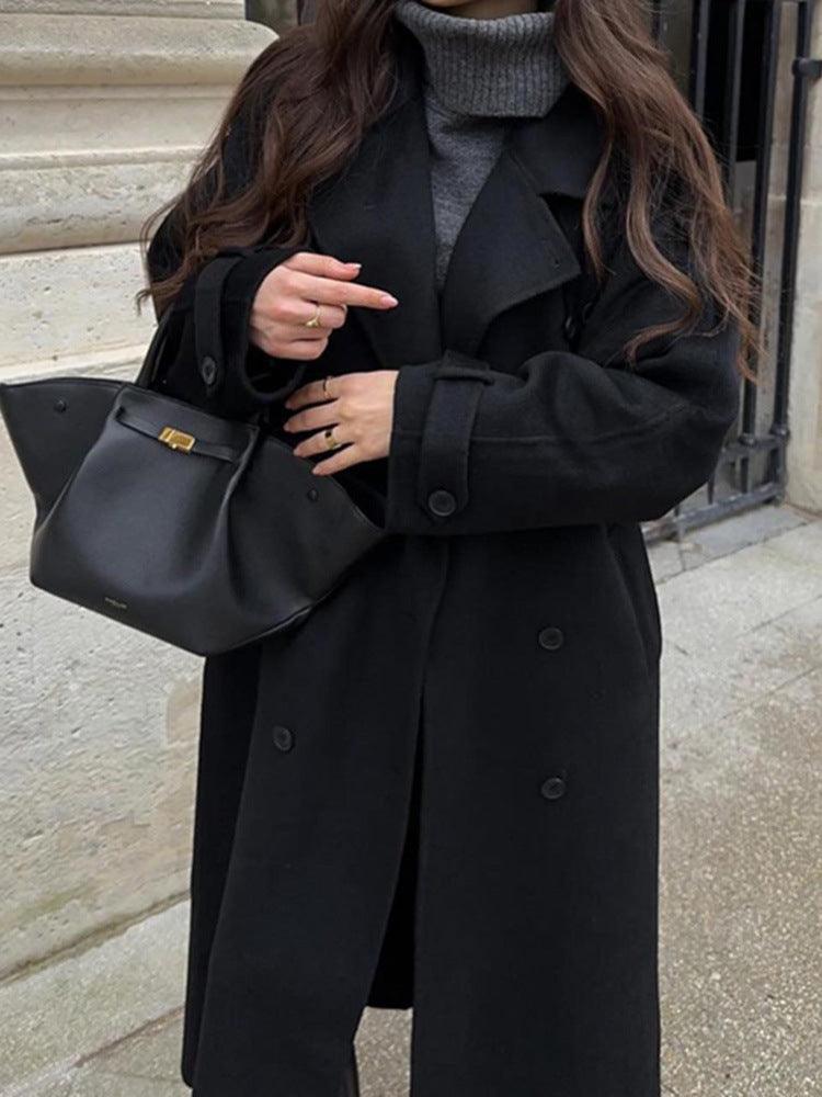 Black long-cut double-breasted coat with notched lapel and flap pockets.