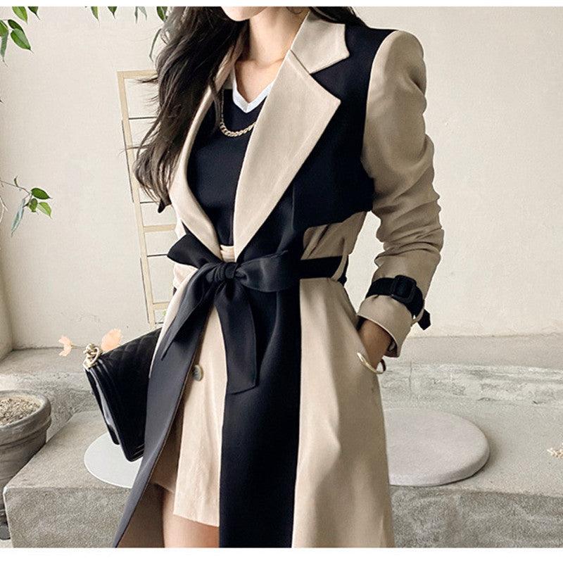 Khaki belted trench coat with black lapel trim and button closure, close-up