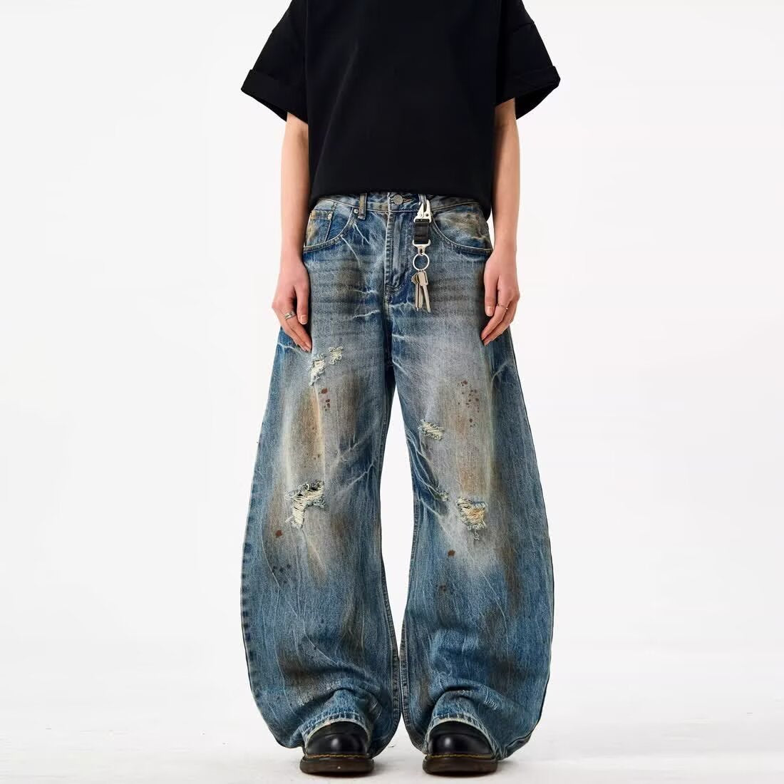 Blue distressed wide-leg jeans with faded stain-dye patches and small knee rips