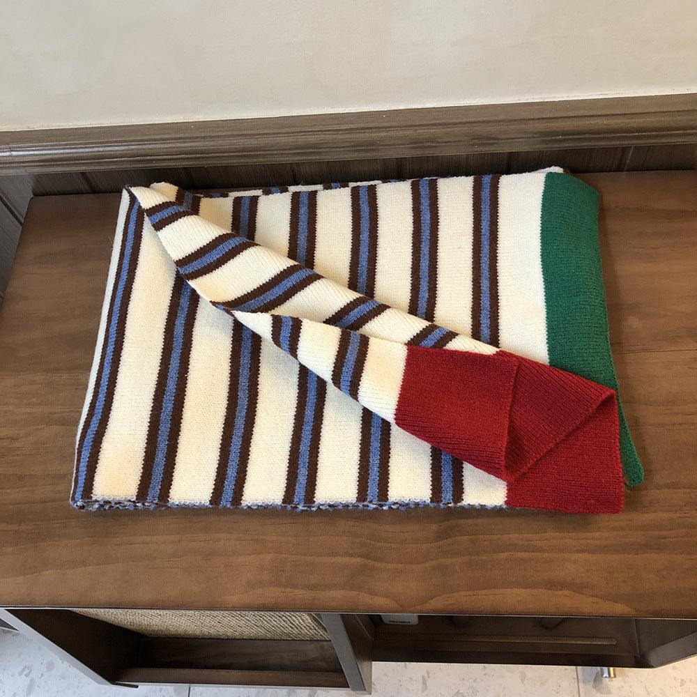 Knitted wool scarf rolled; cream stripes with blue lines and a red end