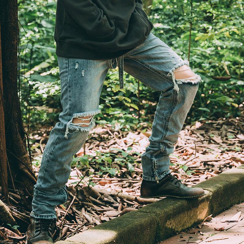 Distressed denim jeans with ripped knees, frayed hems, and ankle-length cuffs