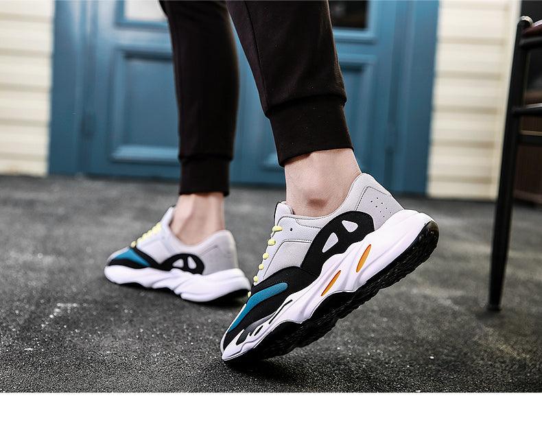 Gray and black lace-up sneakers worn with black pants; black logo cutouts on sides