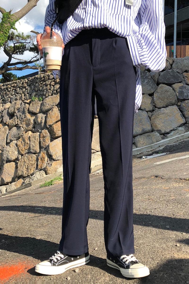 Dark straight suit trousers with front crease, belt loops, and wide straight-leg fit
