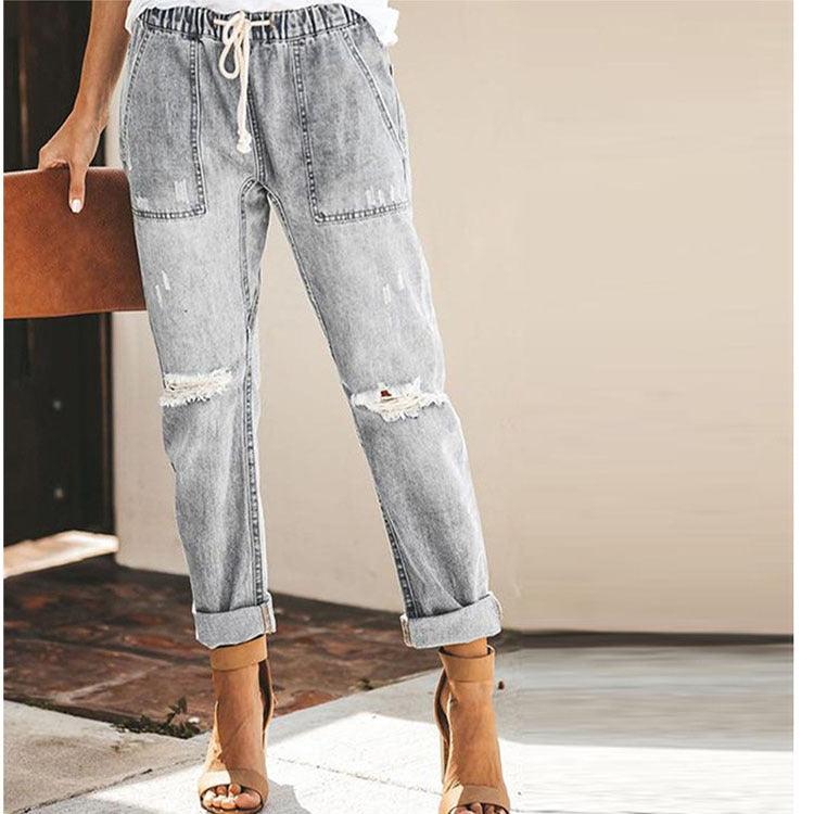 Light gray ripped denim trousers with elastic drawstring waist and cuffed ankles