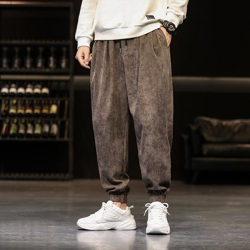 Dark grey corduroy jogger-style trousers with elastic cuffs and drawstring waist