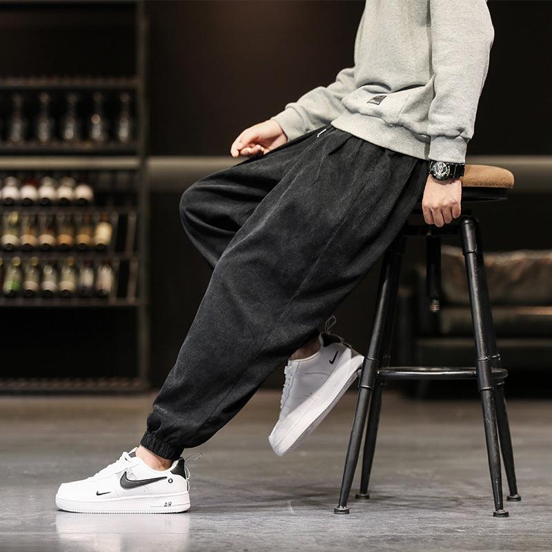 Black corduroy jogger-style trousers with elastic cuffs and relaxed tapered leg
