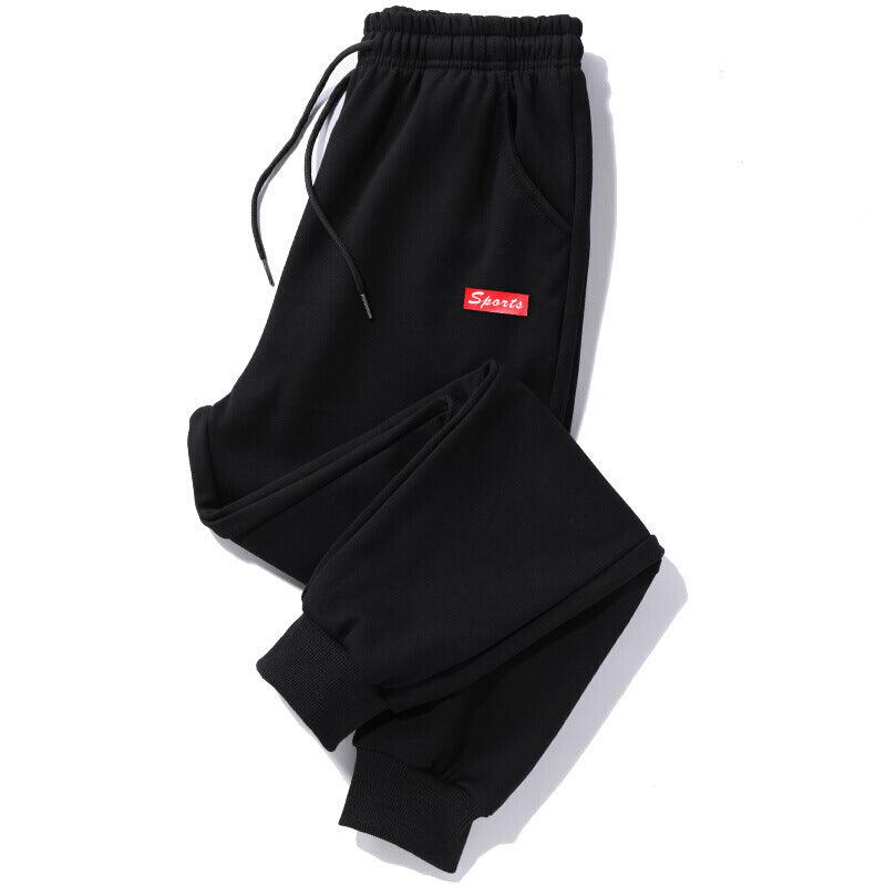 Black jogger trousers with drawstring waist, elastic cuffs, side pocket, and red label tag