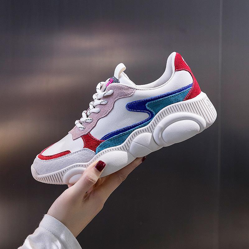 White chunky sneakers with blue side stripes, red trim, and purple lace tag