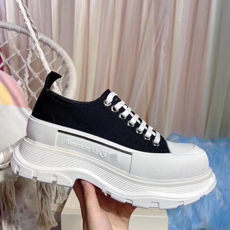 Black low-top canvas sneakers with thick white sole and lace-up eyelets