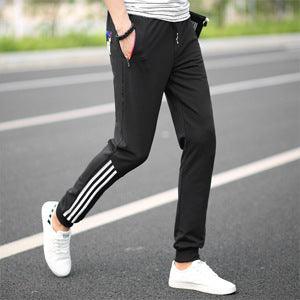 Men's black track pants with white side stripe, tapered ankle cuffs