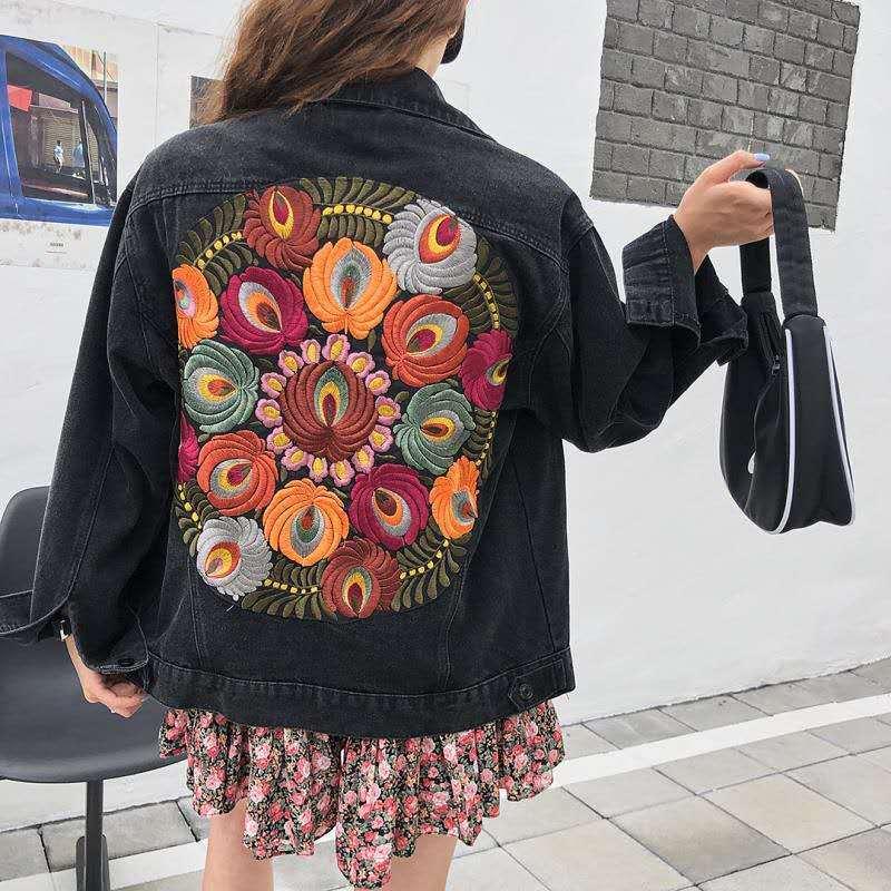 Black denim jacket with vibrant circular floral embroidery on back; oversized sleeves.