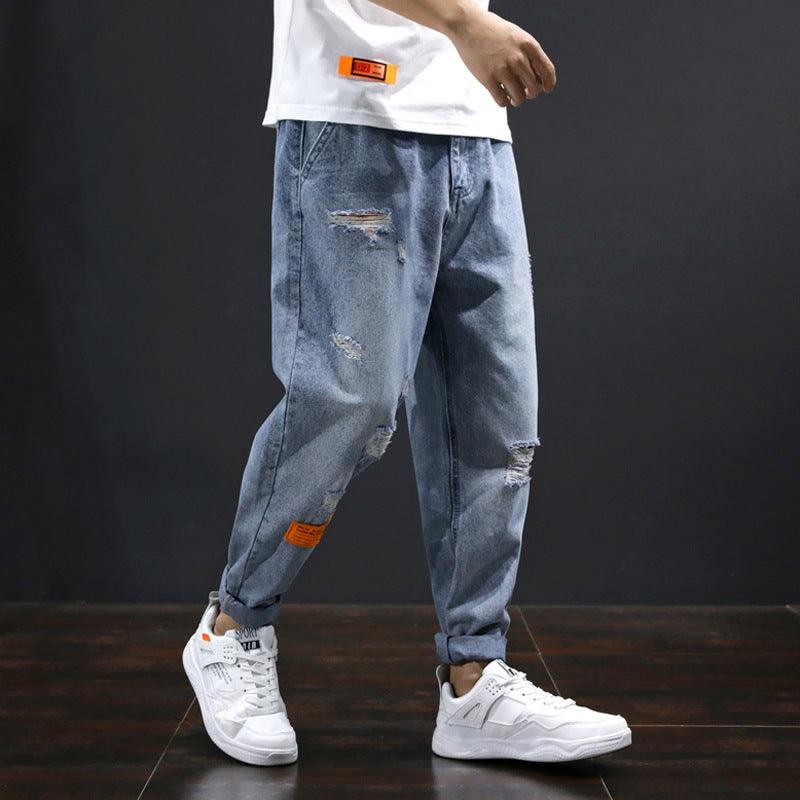 Men's straight casual jeans in medium blue, distressed patches with orange label accents