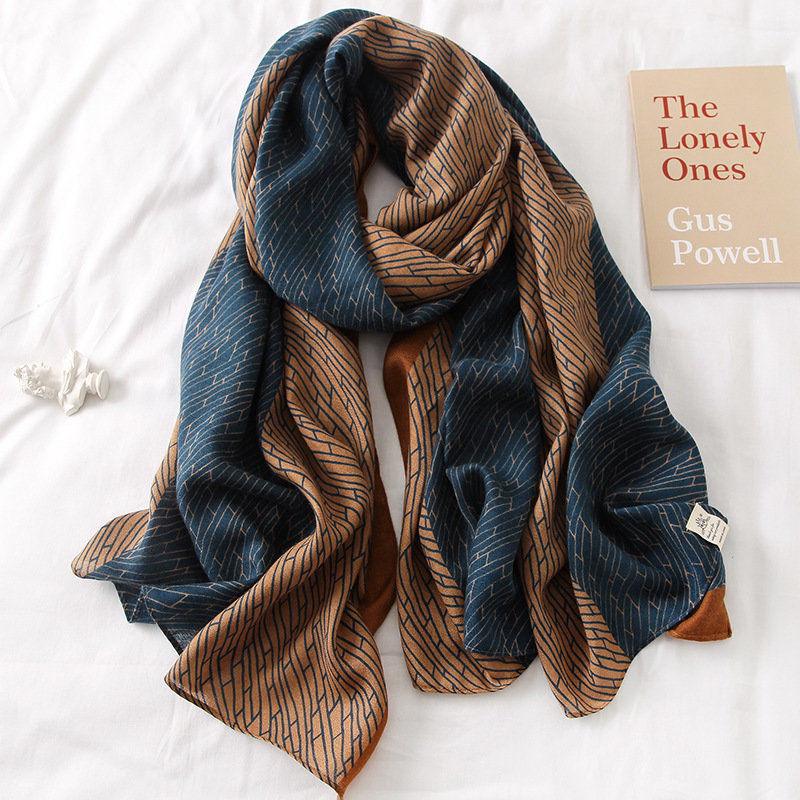 Blue and tan silk scarf with abstract line pattern, loosely wrapped with tags.