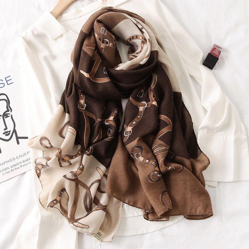 Brown silk scarf with beige and tan horsebit pattern, neatly folded.
